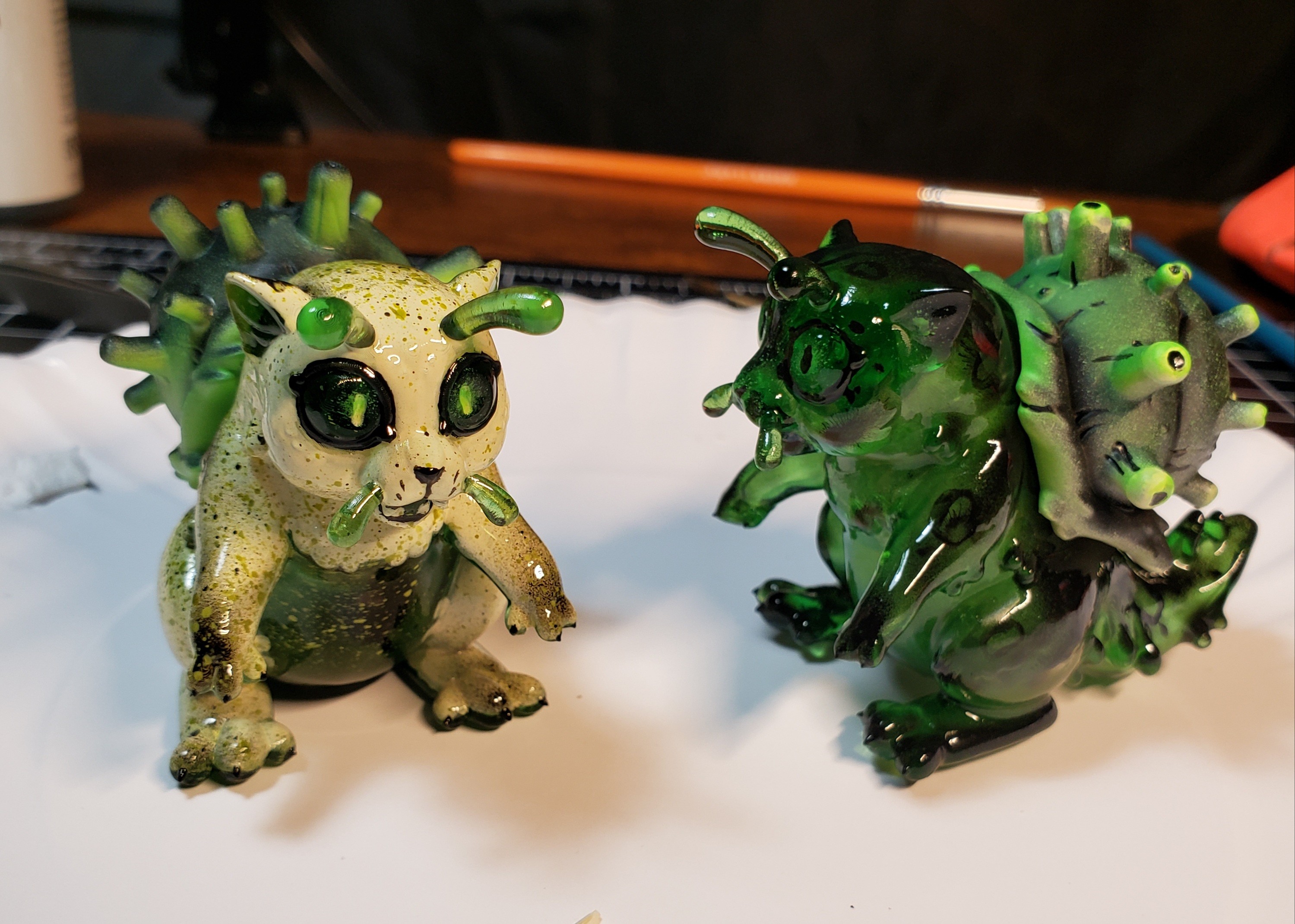 A photo of a sculpture of a snail-cat kaiju with a speckled cream and green color scheme.