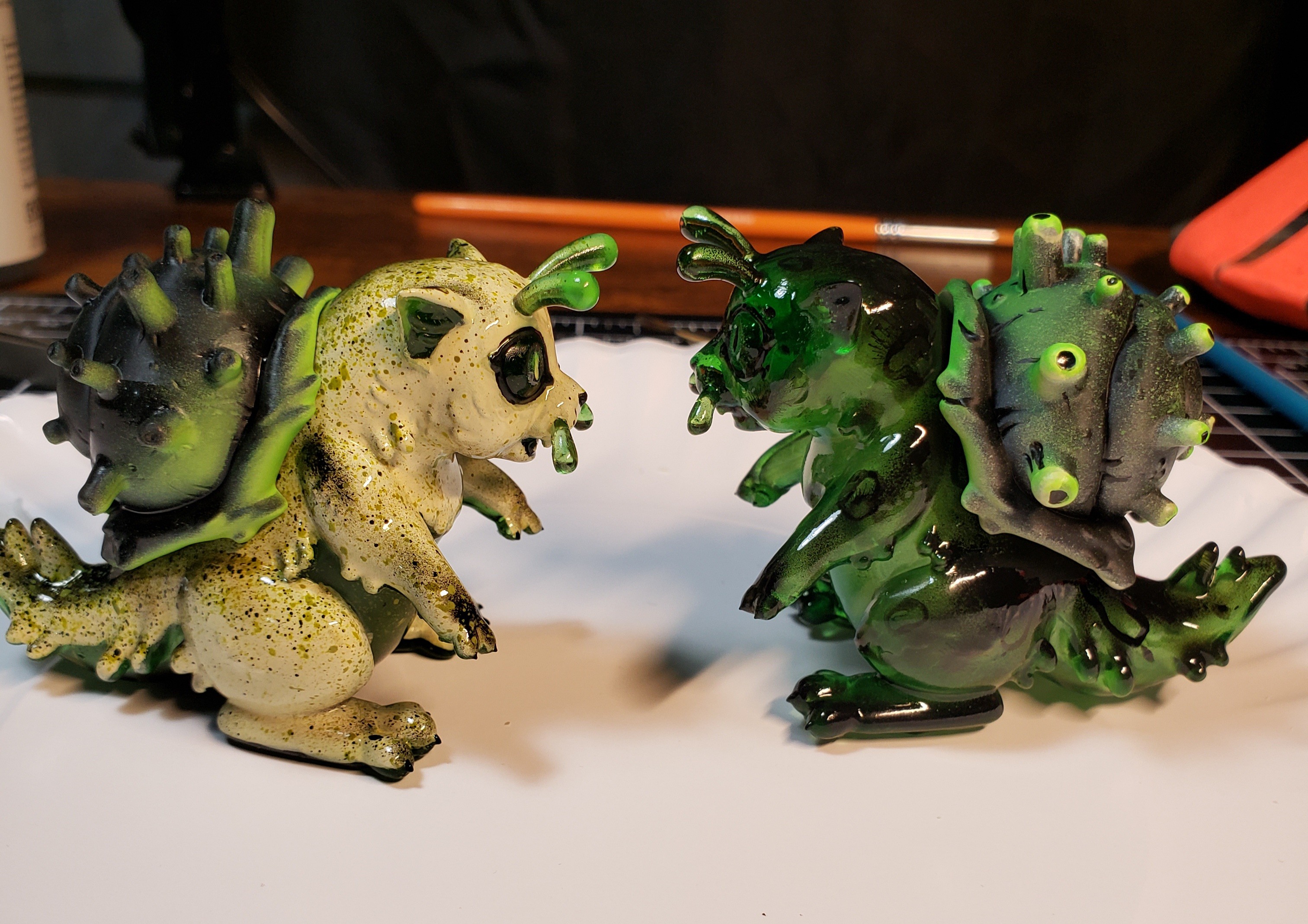 A photo of a sculpture of a snail-cat kaiju with a speckled cream and green color scheme.