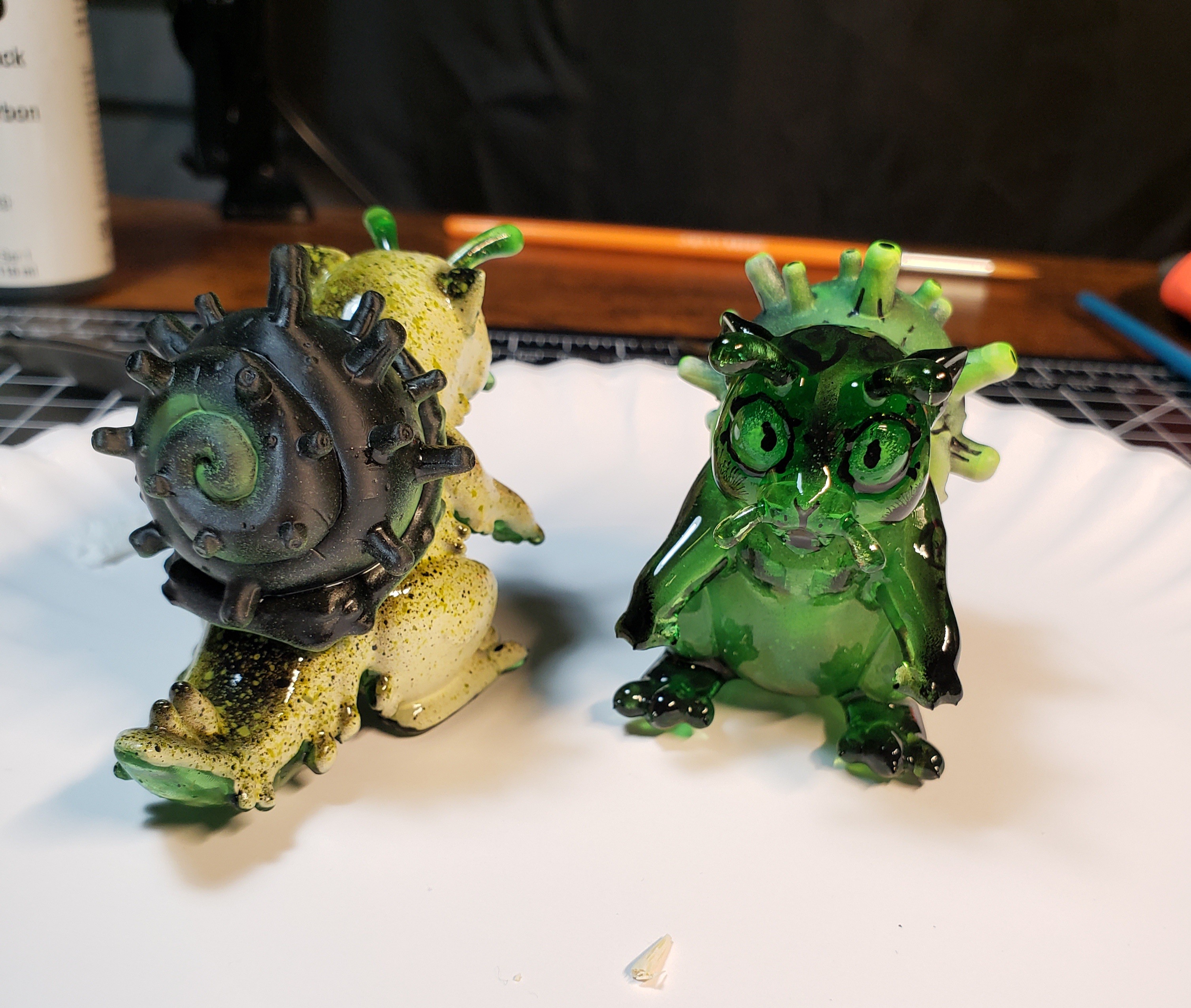 A photo of a sculpture of a snail-cat kaiju with a speckled cream and green color scheme.
