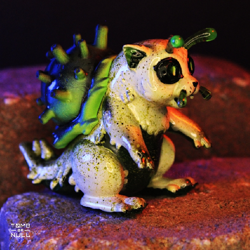 A photo of a sculpture of a snail-cat kaiju with a speckled cream and green color scheme.