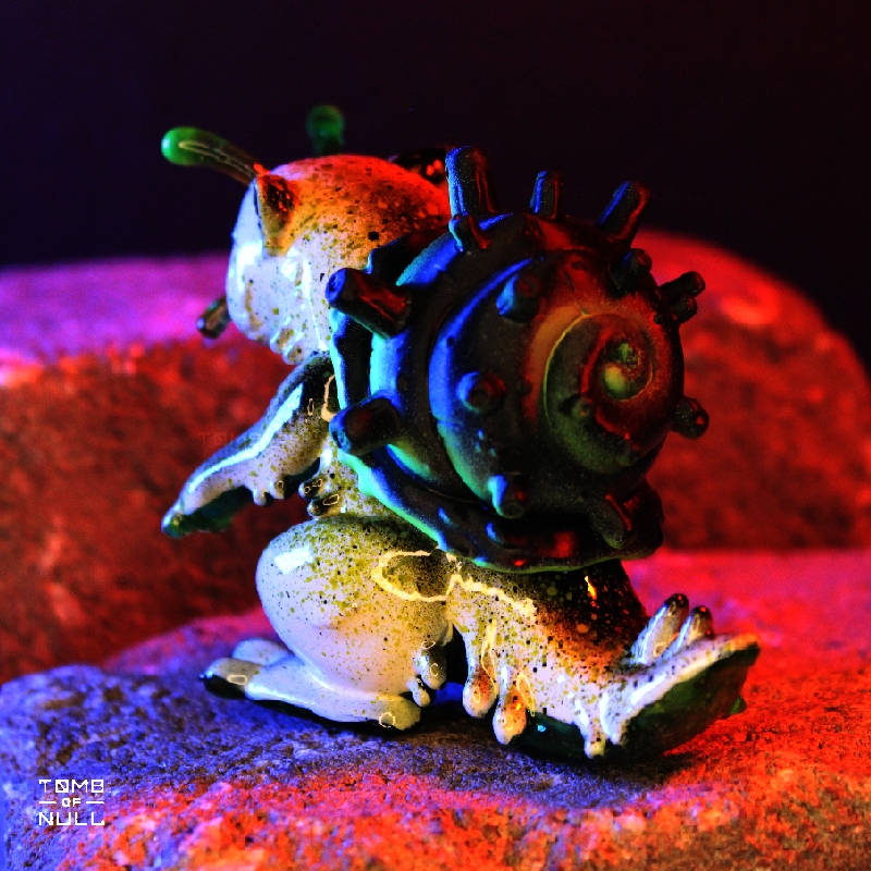 A photo of a sculpture of a snail-cat kaiju with a speckled cream and green color scheme.