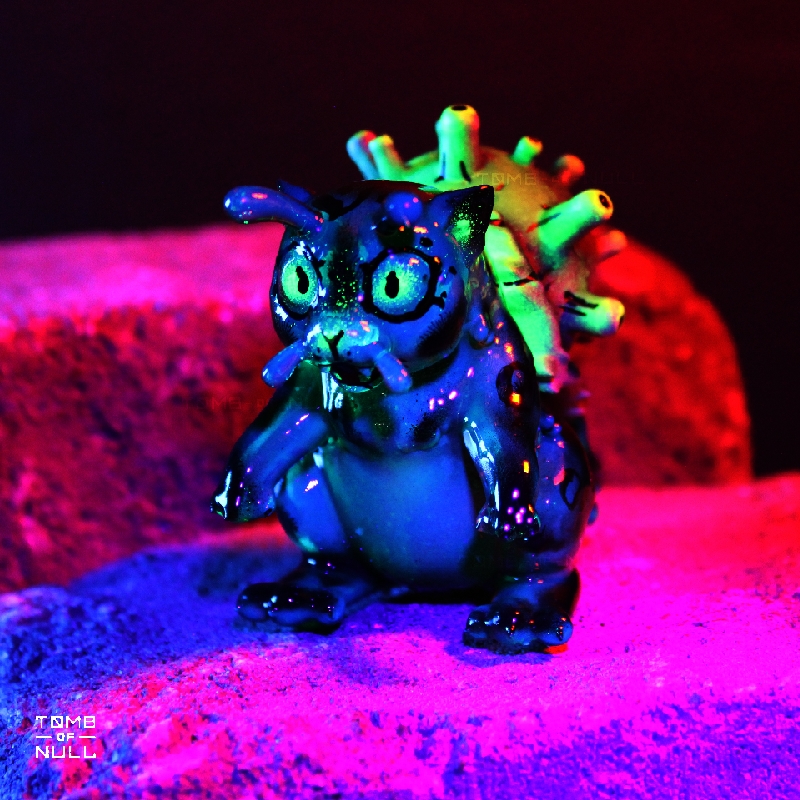 A photo of a sculpture of a snail-cat kaiju with a dark green and black color scheme under UV light, which makes the green florece brightly in the eyes, feelers, and shell.