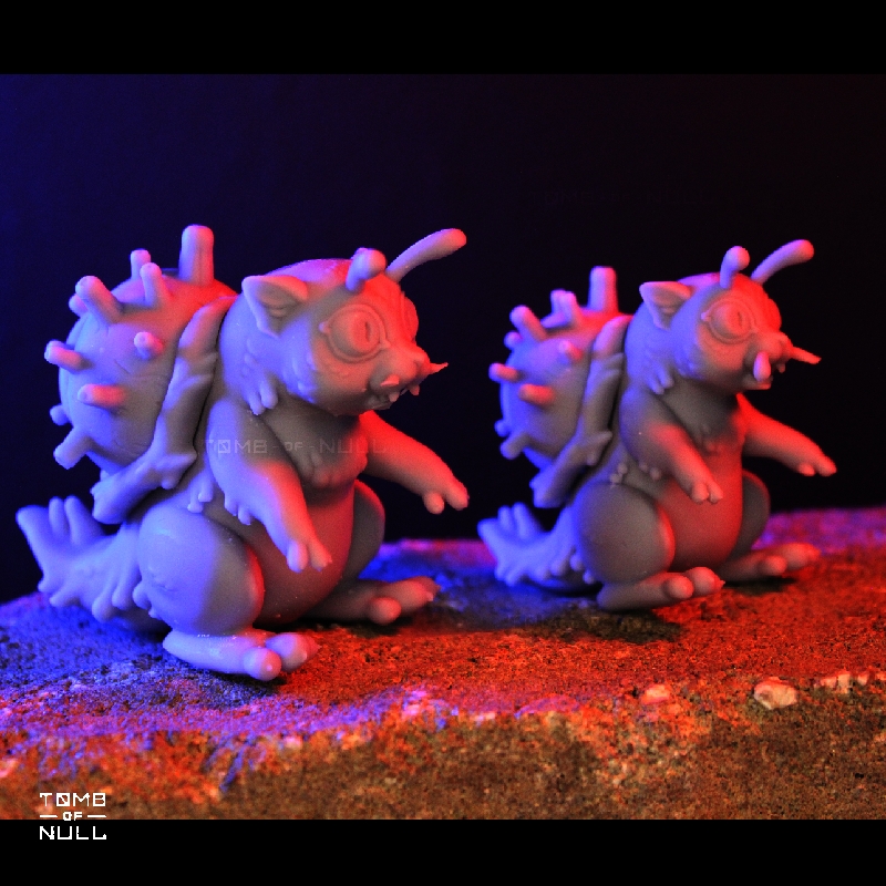 A photo of two snail-cat kaiju sculptures, both a middle grey color. The sculpts have some miss-prints and errors.