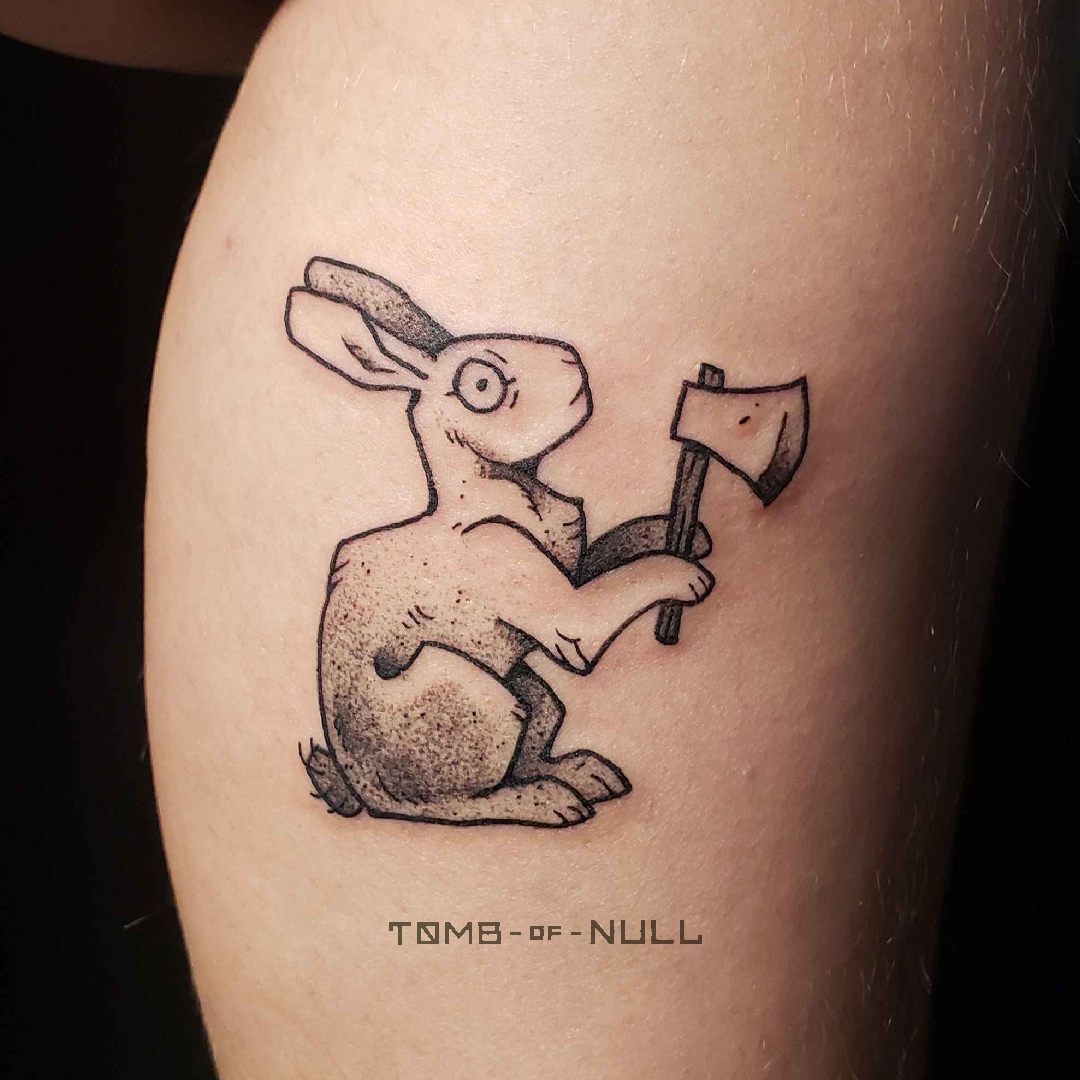 A photo of a tattoo of a rabbit with an axe on light skin.